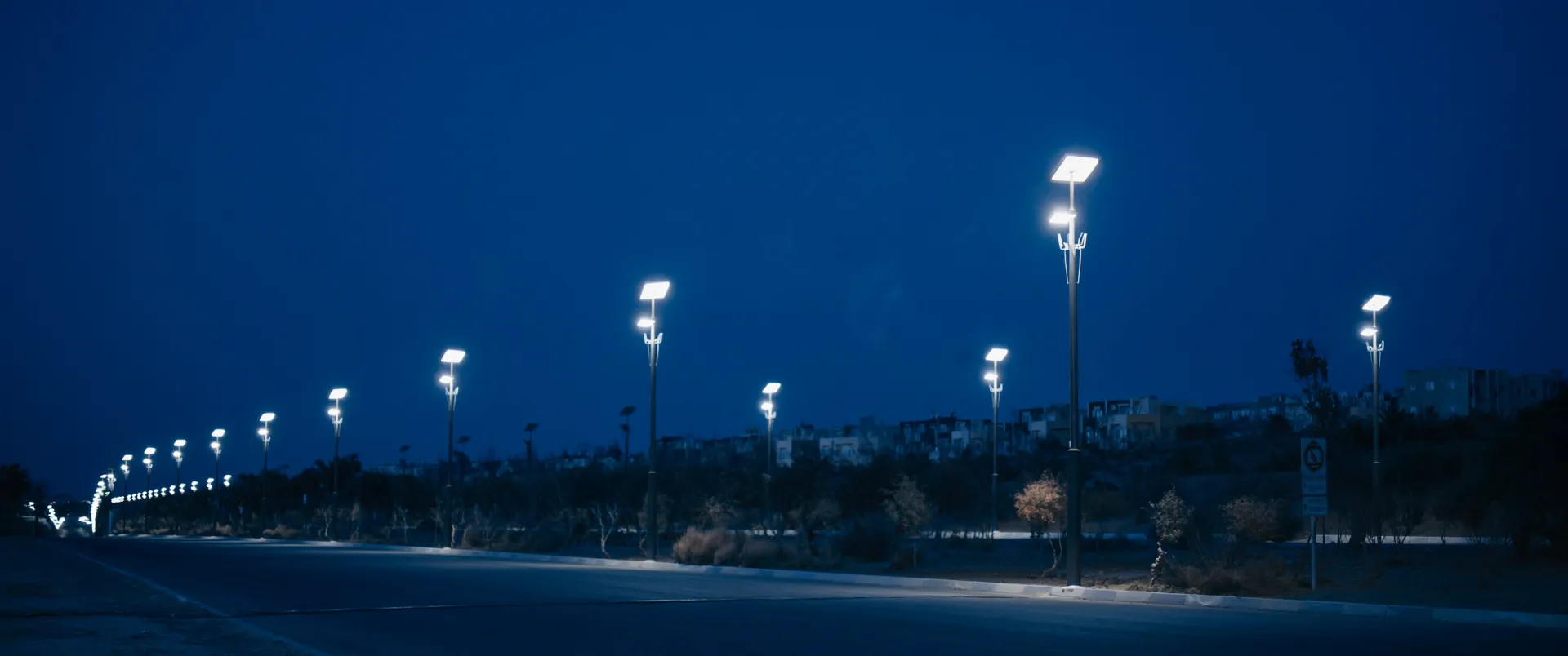 Rue résidentielle marocaine bordée de lampadaires solaires allumés à la tombée du jour