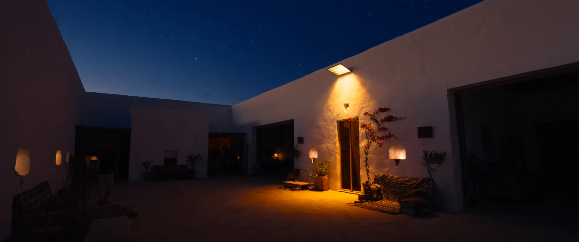 Cour de villa marocaine éclairée par un projecteur solaire au crépuscule